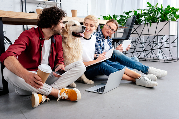 Group of people sitting on the floor with a laptop and documents.